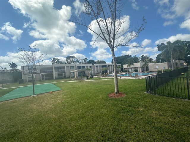 view of property's community with a pool and a lawn