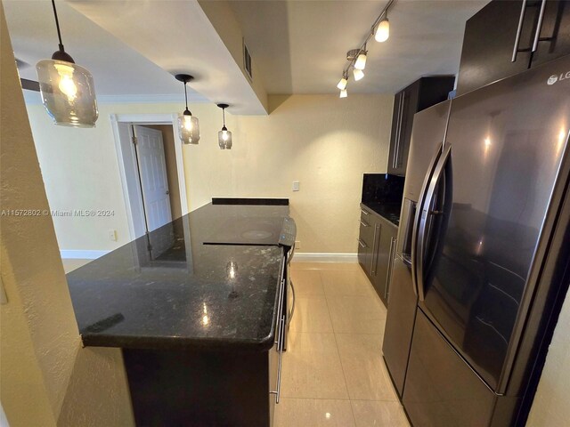 kitchen featuring stainless steel refrigerator with ice dispenser, pendant lighting, light tile patterned floors, and dark stone counters