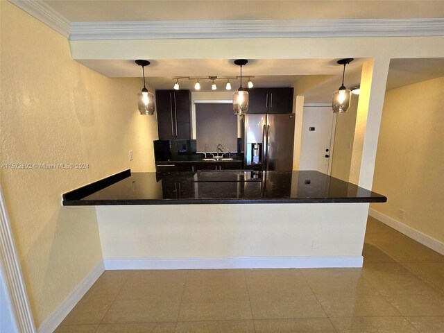 kitchen featuring pendant lighting, sink, crown molding, and stainless steel fridge