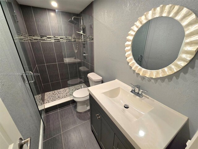 bathroom with a tile shower, vanity, and toilet