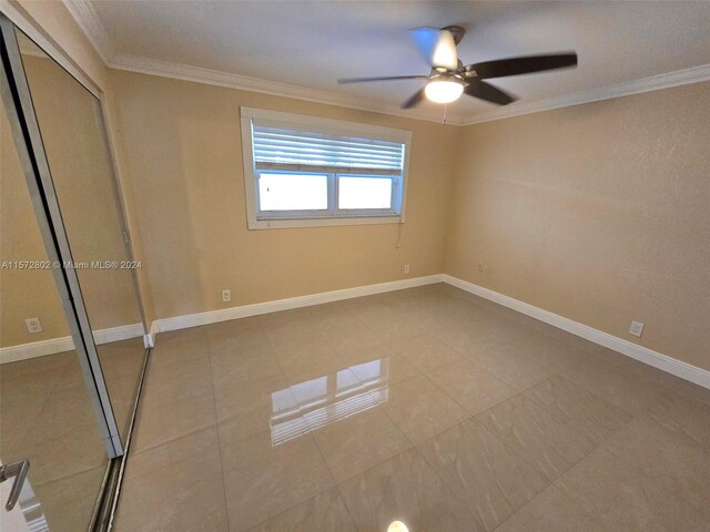 unfurnished bedroom with crown molding, ceiling fan, a closet, and light tile patterned floors