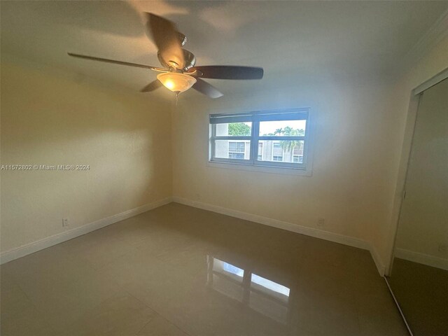 tiled empty room featuring ceiling fan