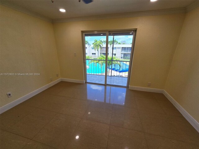 tiled spare room featuring crown molding