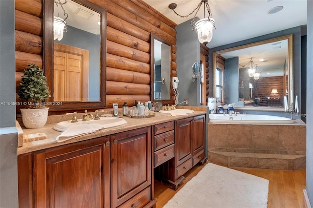 bathroom featuring log walls, hardwood / wood-style floors, vanity, and a relaxing tiled tub