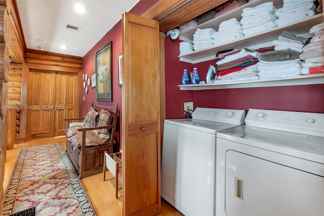 laundry area with light wood-type flooring, washing machine and dryer, and log walls