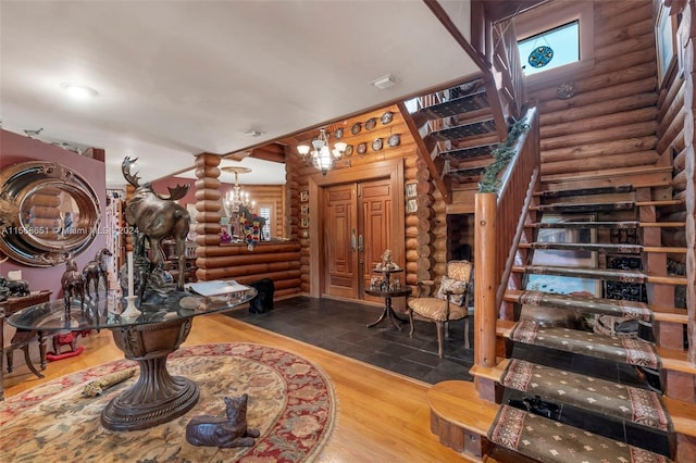 foyer entrance with log walls, an inviting chandelier, and hardwood / wood-style flooring