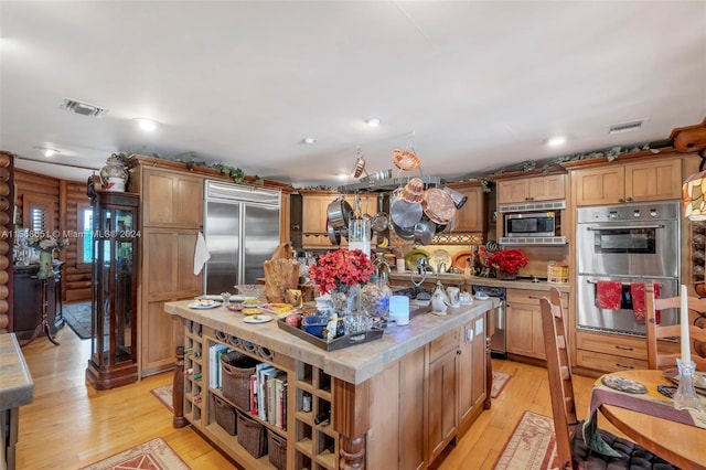 kitchen featuring built in appliances, light hardwood / wood-style flooring, and an island with sink