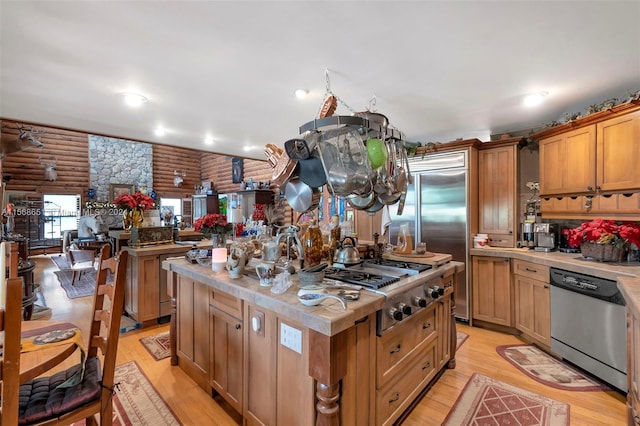 kitchen with light wood-type flooring, appliances with stainless steel finishes, log walls, and a kitchen island