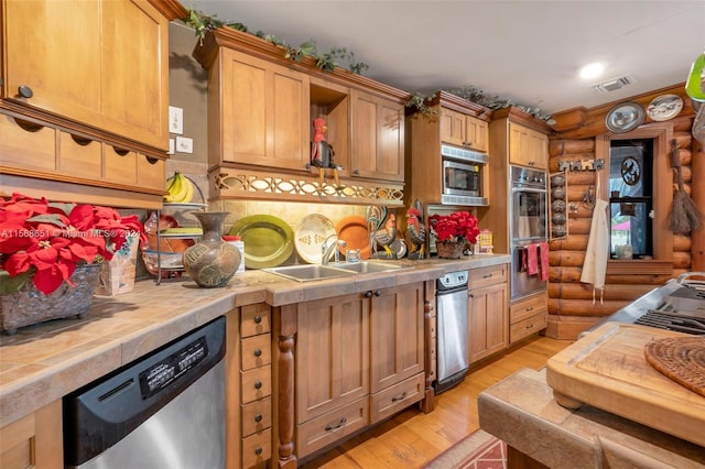 kitchen featuring light hardwood / wood-style flooring, stainless steel appliances, rustic walls, and sink