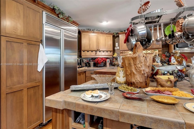 kitchen with stainless steel built in fridge, light hardwood / wood-style floors, and tile counters