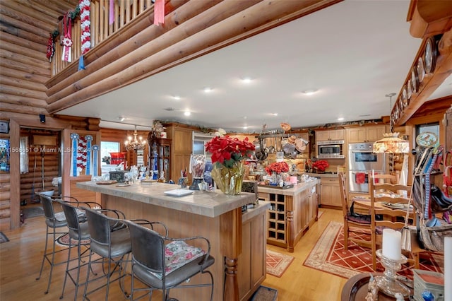 kitchen featuring light wood-type flooring, stainless steel appliances, decorative light fixtures, rustic walls, and a spacious island