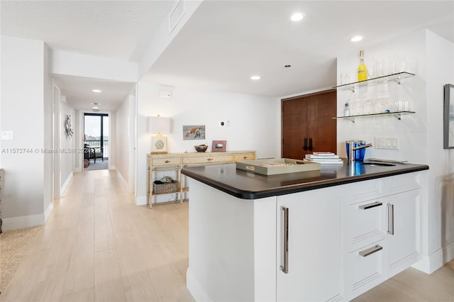 kitchen with light hardwood / wood-style flooring, sink, and white cabinetry