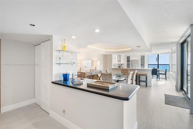 kitchen featuring sink, stainless steel fridge, a raised ceiling, and a water view