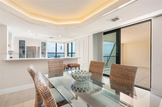 dining room with a water view and a tray ceiling