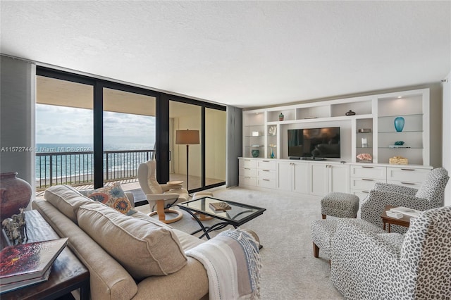 living room with light carpet, expansive windows, built in features, a water view, and a textured ceiling