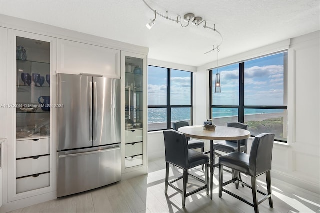 dining area featuring a healthy amount of sunlight, a water view, and light wood-type flooring