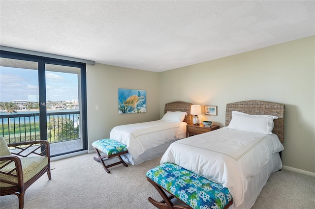 carpeted bedroom featuring a water view, a textured ceiling, and access to exterior