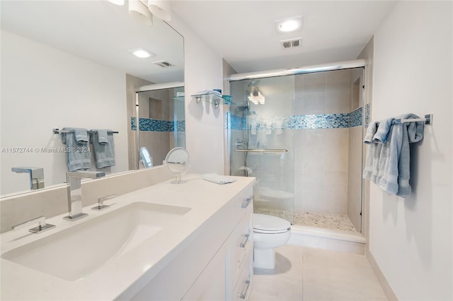 bathroom with a shower with shower door, vanity with extensive cabinet space, toilet, and tile flooring