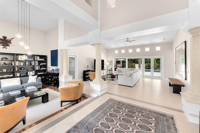 living room featuring ceiling fan, decorative columns, and a high ceiling