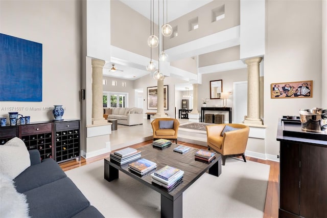 living room featuring decorative columns, a high ceiling, and light wood-type flooring