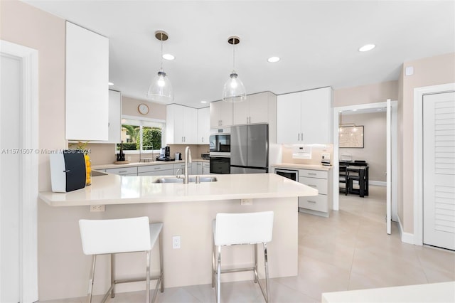 kitchen featuring sink, stainless steel fridge, white cabinetry, and a kitchen breakfast bar