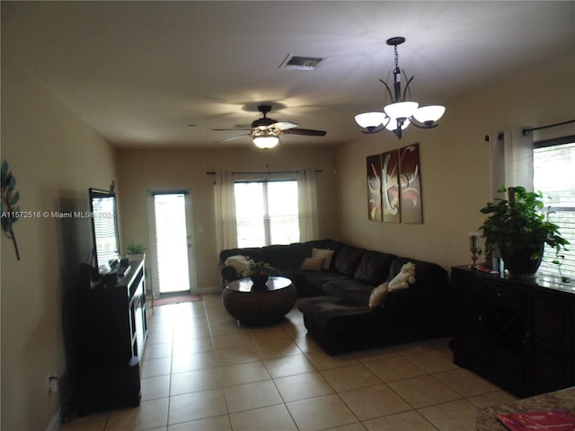 tiled living room with ceiling fan with notable chandelier