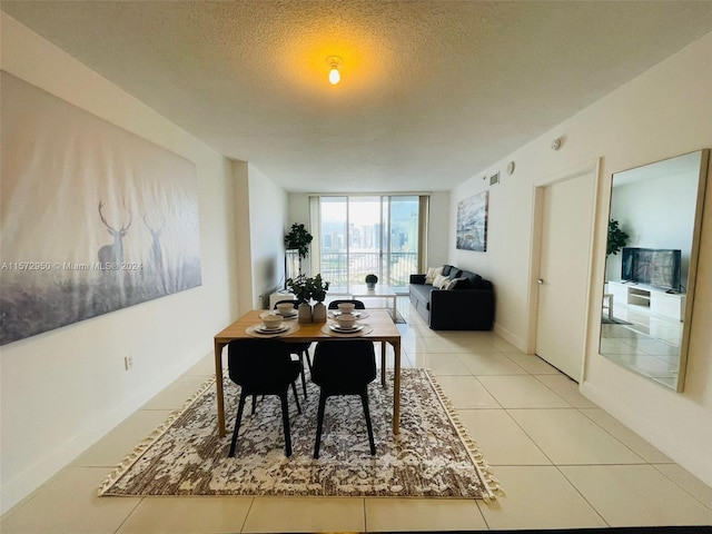 dining area featuring a wall of windows, a textured ceiling, and light tile floors