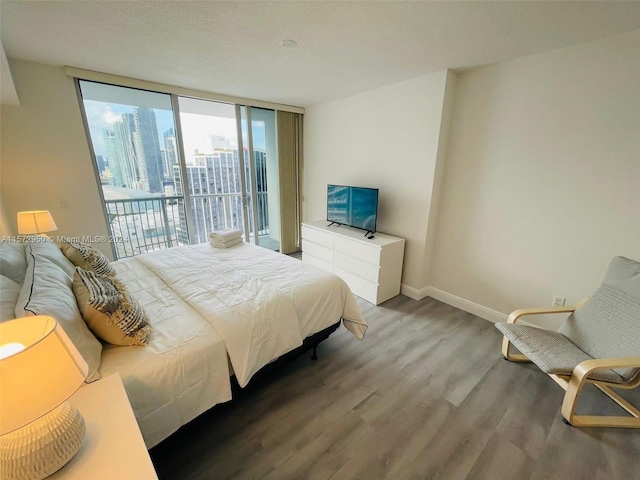 bedroom with hardwood / wood-style flooring, floor to ceiling windows, and access to exterior