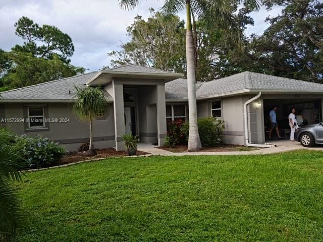 back of property featuring a garage and a lawn