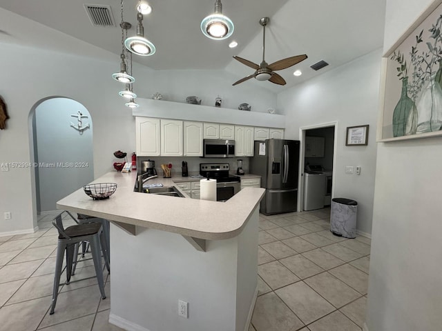 kitchen with high vaulted ceiling, washing machine and dryer, a kitchen bar, stainless steel appliances, and sink