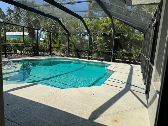 view of pool with a patio and glass enclosure