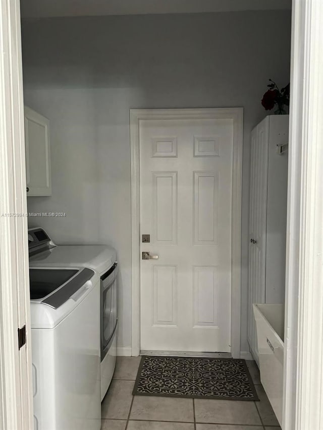 laundry area featuring washing machine and dryer and light tile floors