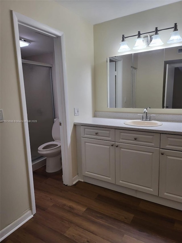 bathroom with hardwood / wood-style floors, vanity, toilet, and an enclosed shower