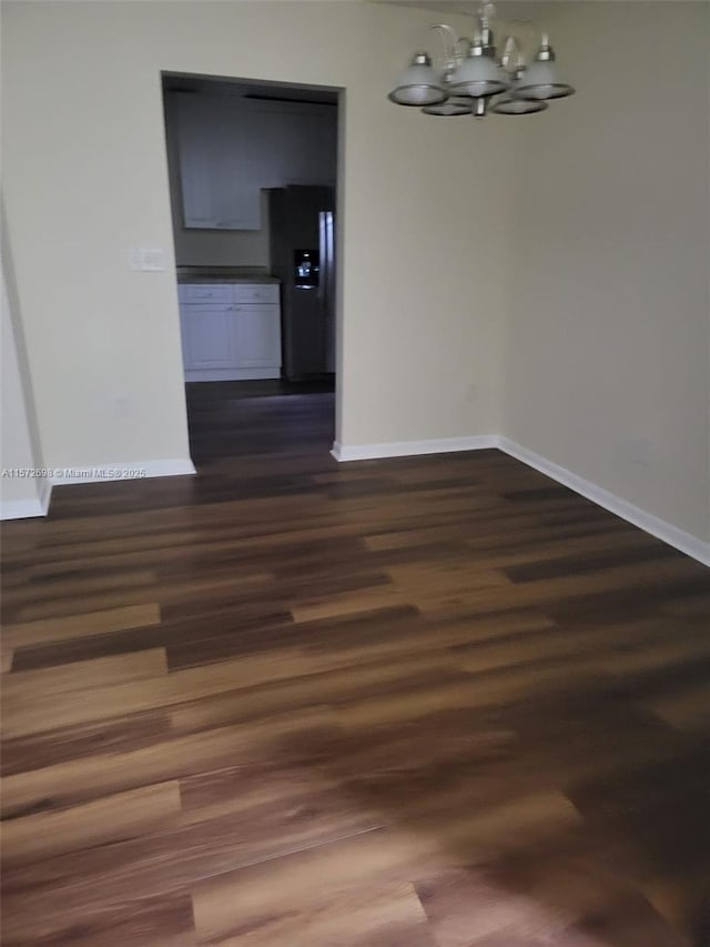 unfurnished dining area featuring dark wood-type flooring and a notable chandelier