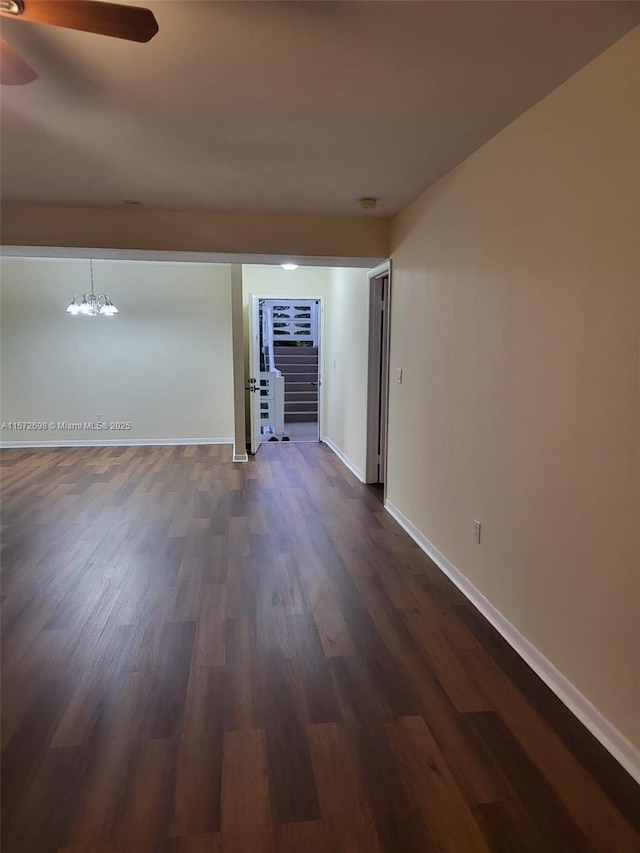 empty room featuring dark wood-type flooring and an inviting chandelier