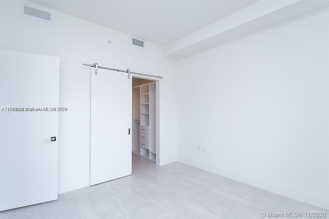 unfurnished bedroom with a barn door, a spacious closet, and a closet