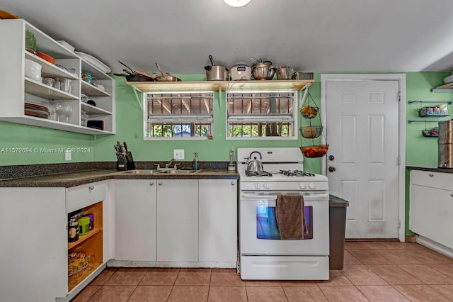 kitchen featuring light tile flooring, white cabinetry, sink, and white range with gas stovetop