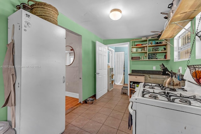 kitchen featuring white appliances, sink, and light tile floors