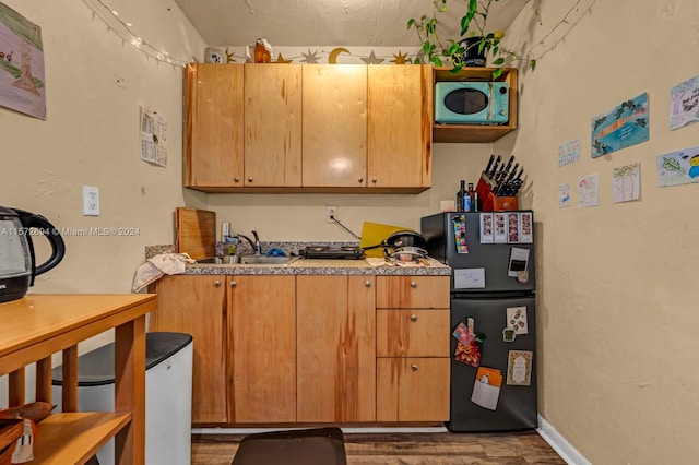 kitchen featuring black refrigerator, sink, and dark wood-type flooring