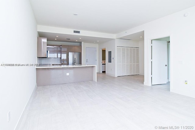 kitchen with kitchen peninsula, tasteful backsplash, stainless steel fridge, and a kitchen bar