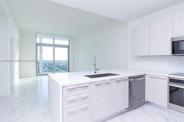 kitchen with appliances with stainless steel finishes, light tile floors, sink, a wall of windows, and kitchen peninsula