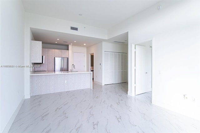 unfurnished living room featuring sink and light tile floors