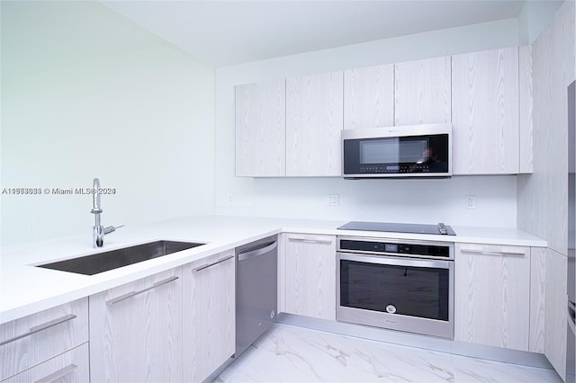 kitchen featuring light brown cabinetry, sink, light tile flooring, and stainless steel appliances