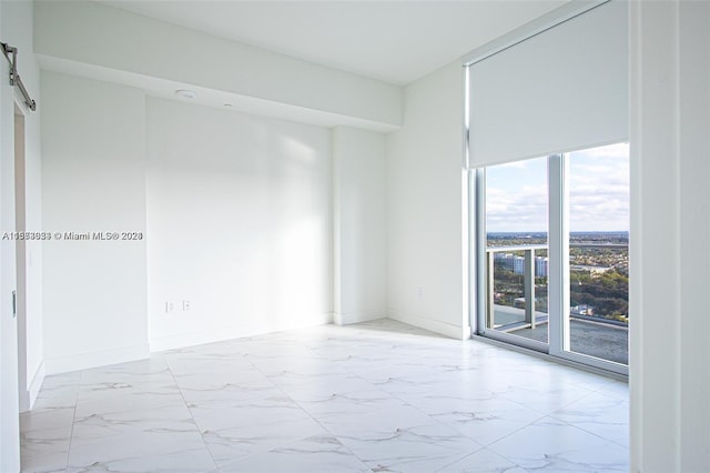 empty room with light tile floors and a barn door