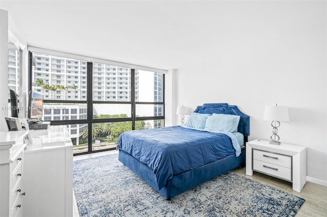 bedroom featuring expansive windows and light hardwood / wood-style floors