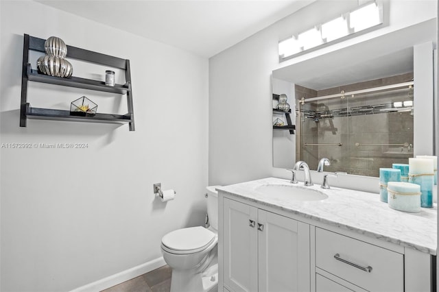 bathroom featuring tile patterned flooring, toilet, a tile shower, and vanity