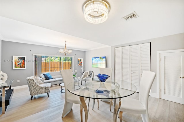 dining area featuring ornamental molding, a notable chandelier, and light wood-type flooring