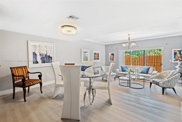 dining space with a notable chandelier and light hardwood / wood-style flooring