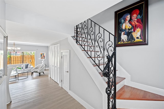 stairway featuring hardwood / wood-style floors and an inviting chandelier