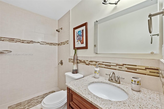 bathroom with toilet, vanity, tile walls, backsplash, and tiled shower